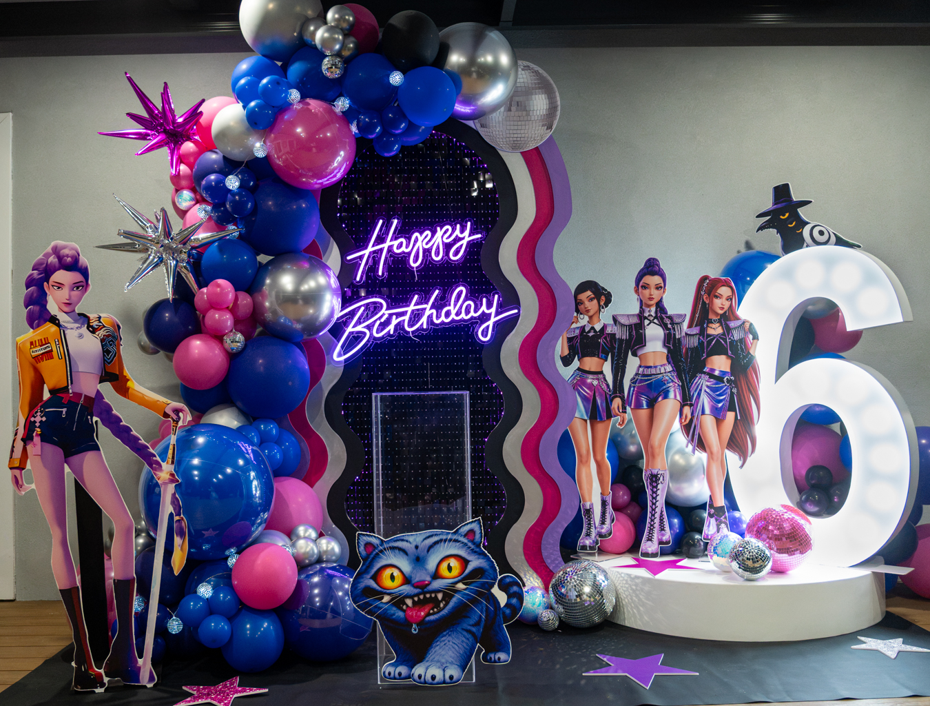 K-pop sixth birthday styling with a wavy backdrop, pink and blue balloons, character cut-outs and disco balls